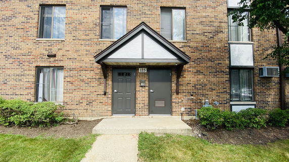 Front view of a brick apartment building with two doors and windows.