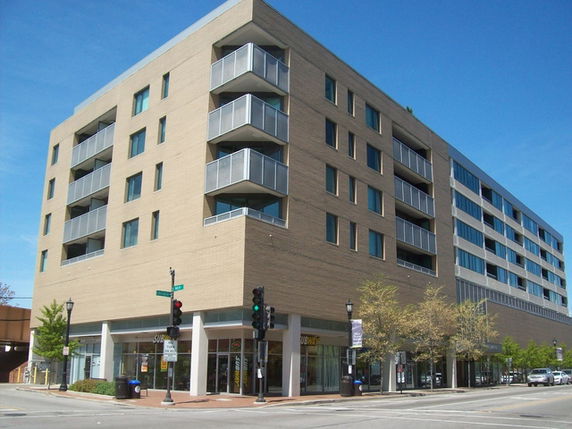 Front view of a multi-story building with balconies and a commercial space on the ground floor.