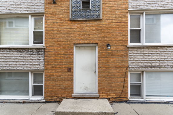 Front view of a multi-story brick building with a central door and multiple windows.