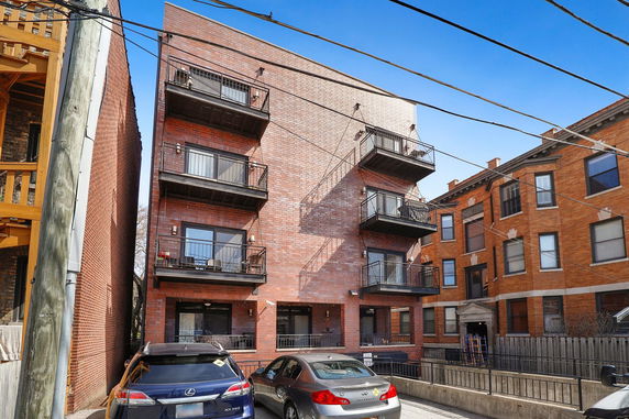 Front view of a multi-story brick building with balconies.