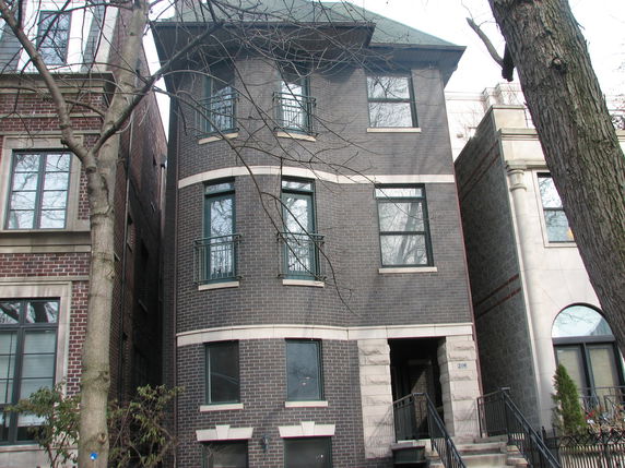 Front view of a multi-story brick building with multiple windows and an entrance staircase.