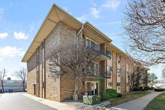 Front view of a multi-story brick apartment building with balconies.
