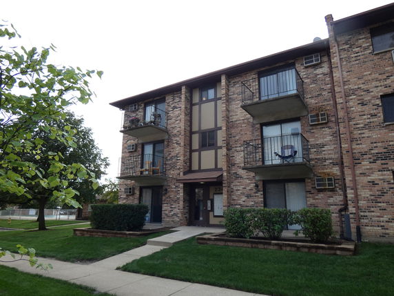 Front view of a multi-story brick apartment building with balconies.