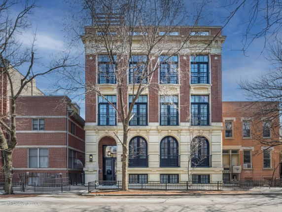 Front view of a multi-story brick building with large arched windows.