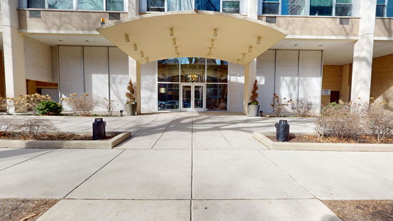 Front view of a building entrance with a large canopy and glass doors.