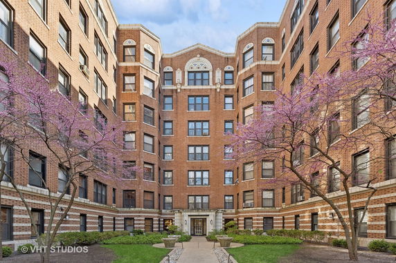 Front view of a multi-story apartment building with brick facade and decorative elements.