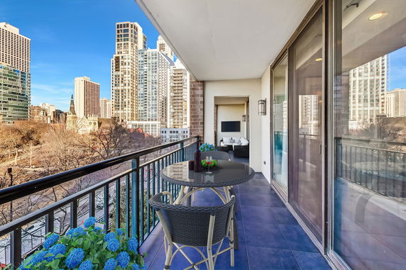 Apartment balcony with outdoor seating and view of city skyscrapers.
