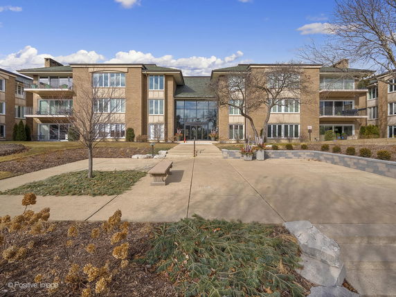 Front view of a multi-story apartment building with balconies and large windows.