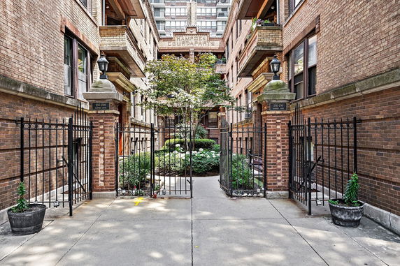 Front view of an apartment building with brick structure and enclosed courtyard.