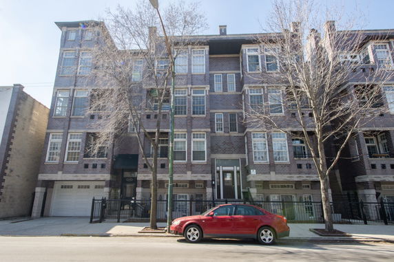 Front view of a multi-story apartment building with brick exterior and large windows.