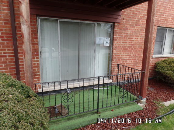 Front view of a brick building with large glass sliding doors and a small fenced porch area.