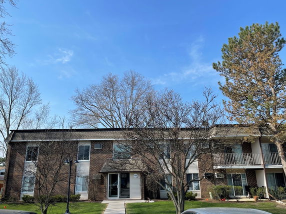 Front view of a two-story residential building with a brick facade and balconies.