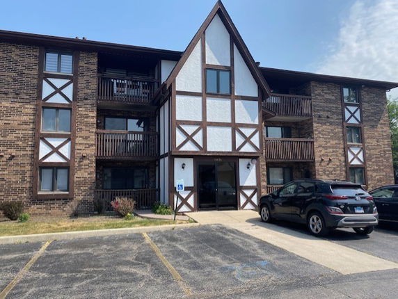 Front view of a three-story apartment building with a Tudor architectural style.