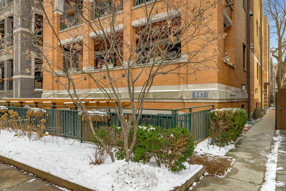 Front view of a multi-story brick building with balconies and a snow-covered sidewalk.