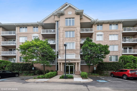 Front view of a multi-story apartment building with balconies and a symmetrical design.