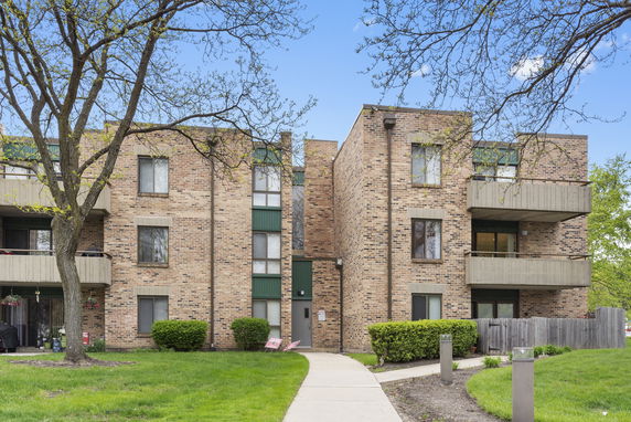 Front view of a multi-story brick apartment building with balconies.
