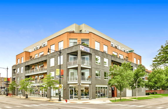 Front view of a multi-story building with a combination of brick and glass elements.