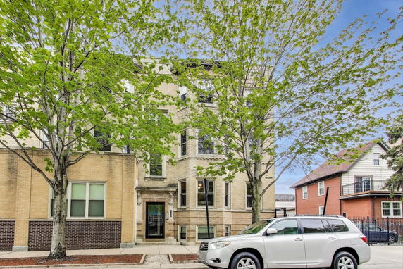 Front view of a multi-story brick building with large windows.
