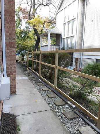 Side view of a two-story house with large windows and a fenced path.