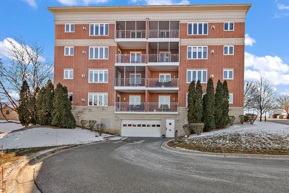 Front view of a multi-story brick apartment building with balconies.
