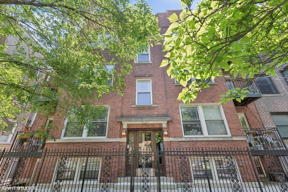 Front view of a multi-story brick building with a metal fence.