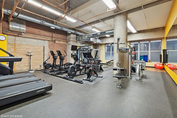 Indoor gym area with exercise equipment, including treadmills, ellipticals, and weight machines.