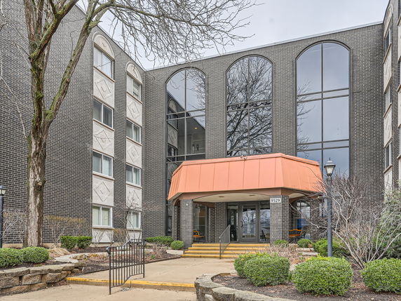 Front view of a multi-story building with arched windows and an orange awning over the entrance.