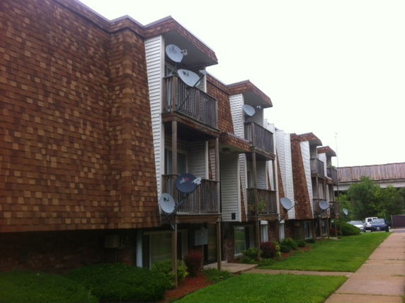 Front view of an apartment building with wooden balconies and satellite dishes.