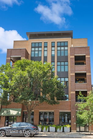 Front view of a multi-story building with large windows and a brick facade.