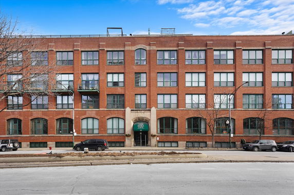 Front view of a multi-story brick apartment building with large windows.