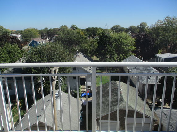 Panoramic view from a balcony overlooking residential houses and trees.