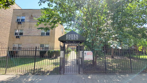 Front view of a multi-story brick residential building with a gated entrance.
