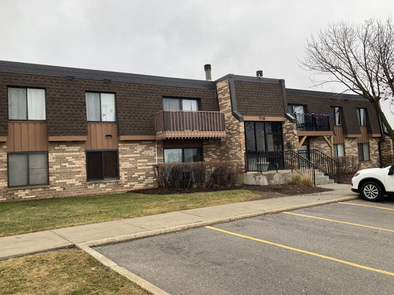 Front view of a two-story apartment building with brick and shingle exterior.