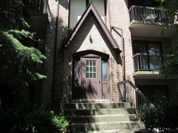 Front view of a multi-story building with a brick facade and balconies.