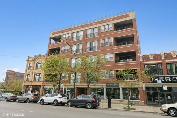 Front view of a multi-story brick building with retail space on the ground floor.