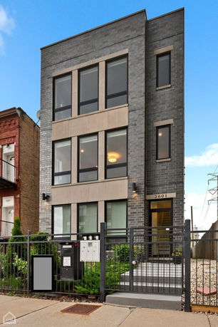 Front view of a modern multi-story building with large windows and a gated entrance.