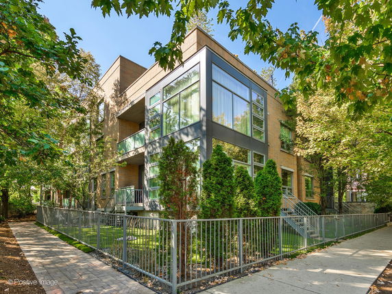 Front view of a modern two-story building with large windows and a metal fence.