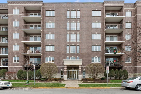 Front view of a multi-story brick apartment building with balconies.