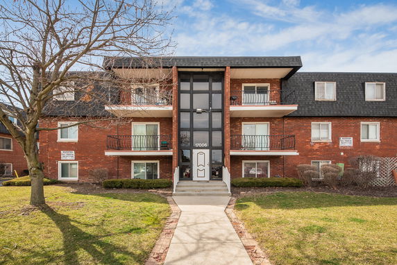 Front view of a brick three-story apartment building with balconies.