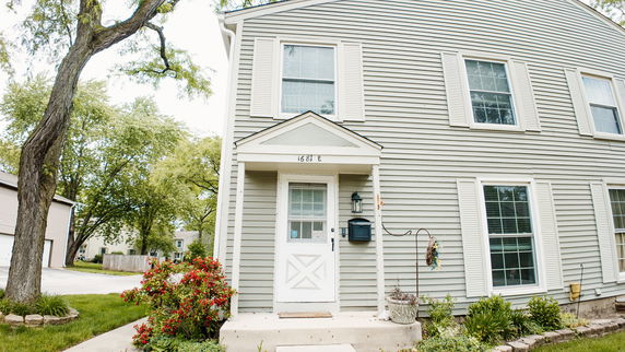 Front view of a two-story house with a white door and siding.