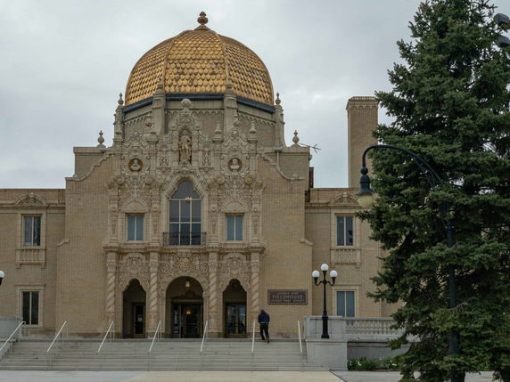 Front view of a building with an ornate facade and a golden domed roof.