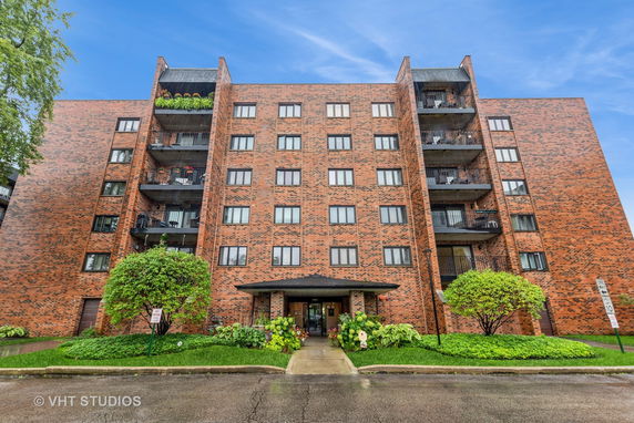 Front view of a multi-story brick apartment building with balconies.