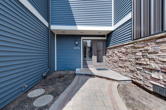 Front view of a building entrance with blue siding and stone accents.