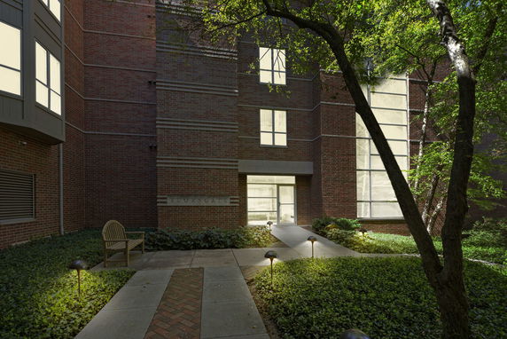 Front view of a multi-story brick building entrance with large windows.