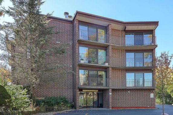 Front view of a multi-story brick apartment building with balconies.
