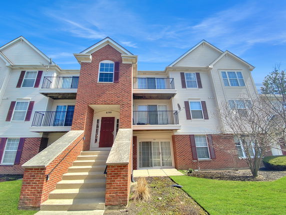 Front view of a three-story residential building with brick and siding exterior.