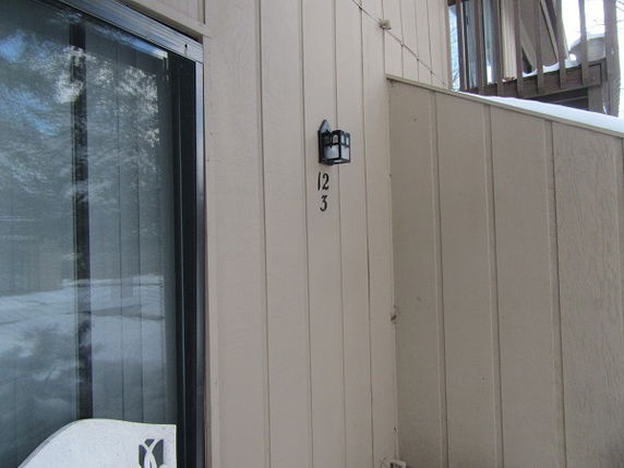 Side view of a building exterior with vertical wood siding and a wall-mounted light fixture.