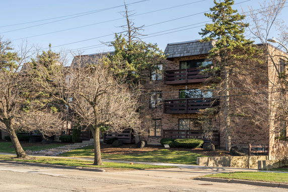 Front view of a multi-story brick apartment building with balconies.