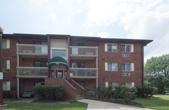 Front view of a three-story apartment building with brick exterior and balconies.