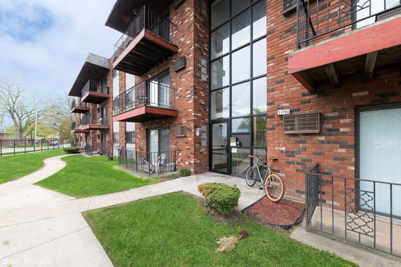Exterior view of a brick apartment building with balconies and large glass windows.